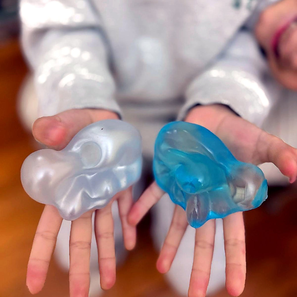 A child squeezing a pearl and a blue Squishlotte Original squishy